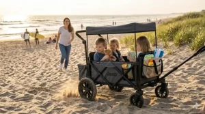 A heavy-duty all-terrain wagon stroller with large wheels and a sandy beach bag navigating through loose sand on a beach.