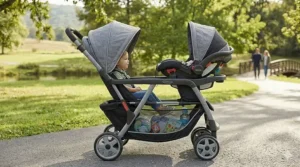 A tandem-style Graco double stroller travel system with one seat positioned in front of the other.