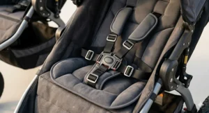 Detailed view of a five-point safety harness and padded seat inside a rugged all-terrain stroller.