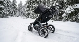 All-terrain stroller with deep-tread tires navigating through a snowy park sidewalk in winter.