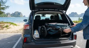 A lightweight folding stroller designed for beach travel being packed into an SUV trunk.