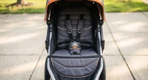 Interior view of a lightweight jogging stroller featuring a padded reclining seat and a secure five-point safety harness.