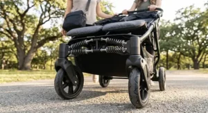 Close-up of front swivel wheels and suspension on a budget side-by-side double stroller for twins.