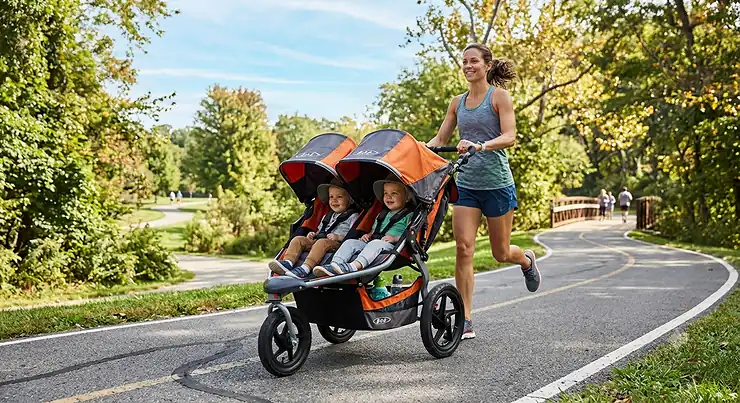 Side-by-side jogging double stroller for running with twins on a paved park trail