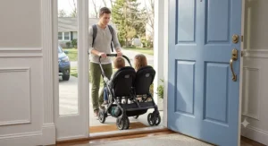 A narrow side-by-side double stroller passing effortlessly through a standard American doorway.