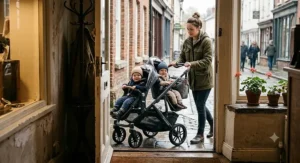 Parent pushing an inline tandem double stroller for twins smoothly through a narrow doorway.