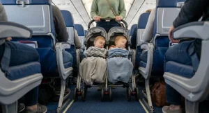 Lightweight travel double stroller for toddlers being wheeled down a narrow airplane aisle.