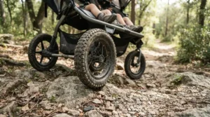 Close-up of the wheels on an all-terrain twin jogging stroller for trail runs navigating a rocky mountain trail.