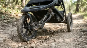 The heavy-duty suspension system on an all-terrain twin jogging stroller for trail runs during an outdoor workout.