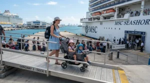 Rolling a compact twin stroller for cruise vacations up the embarkation gangway onto a large cruise ship.