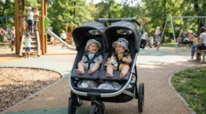 Sunshades extended to block midday rays on an infant twin stroller under $400 at a neighborhood park.