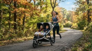 A parent pushing a jogging double stroller for marathon training parents along a paved park path during sunrise