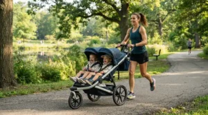 A mother using a twin jogging stroller for running with twins along a sunny park trail.